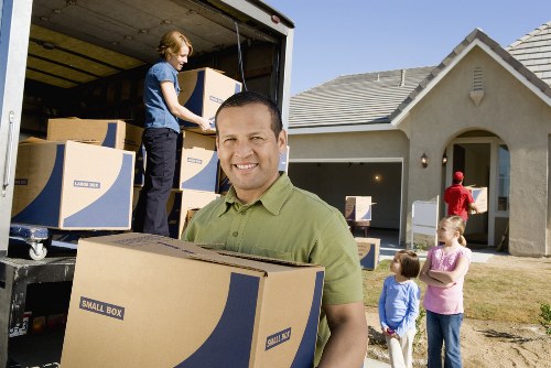Removal workers wearing PPE while carrying furniture carefully
